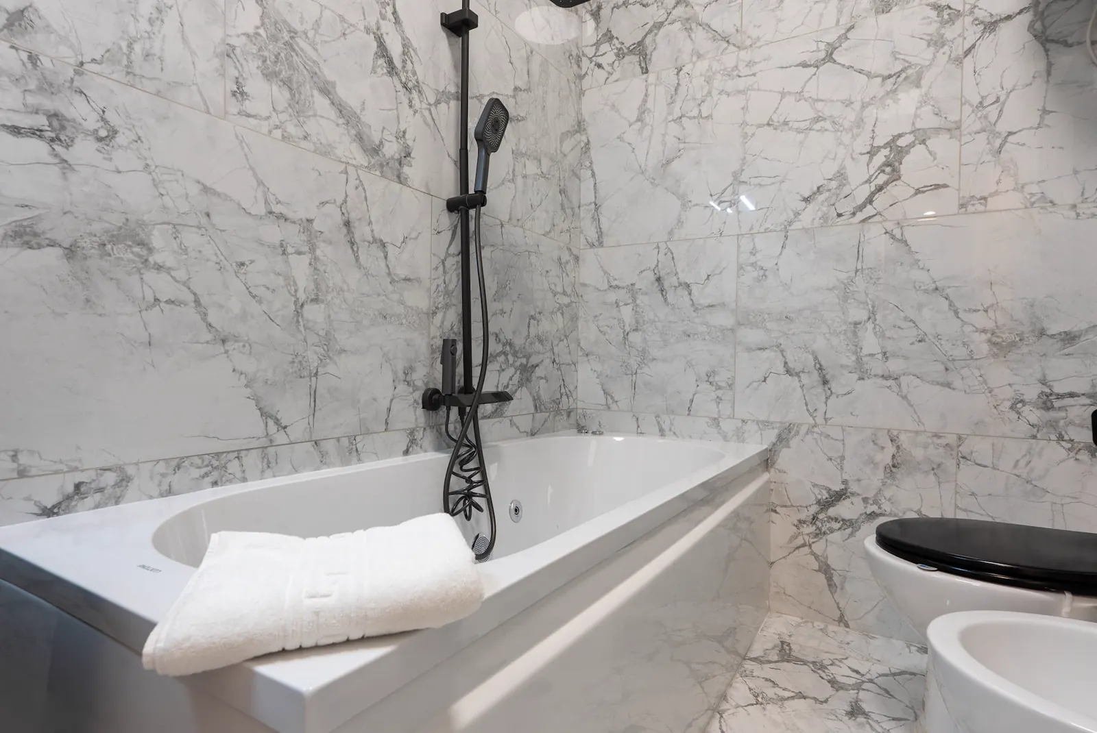 Bagno con rivestimenti marmorei e vasca